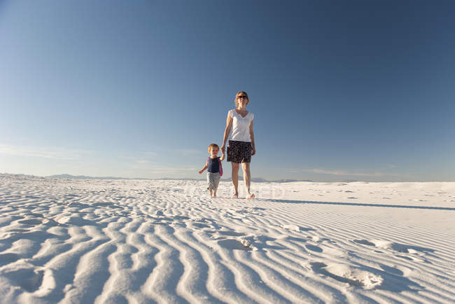 Мать и сын, гуляющие по дюне, Национальный памятник Уайт-Сэндс, Нью-Мексико, США — стоковое фото