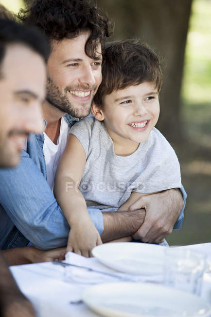 Padre e hijo pequeño con amigo en la comida al aire libre - foto de stock