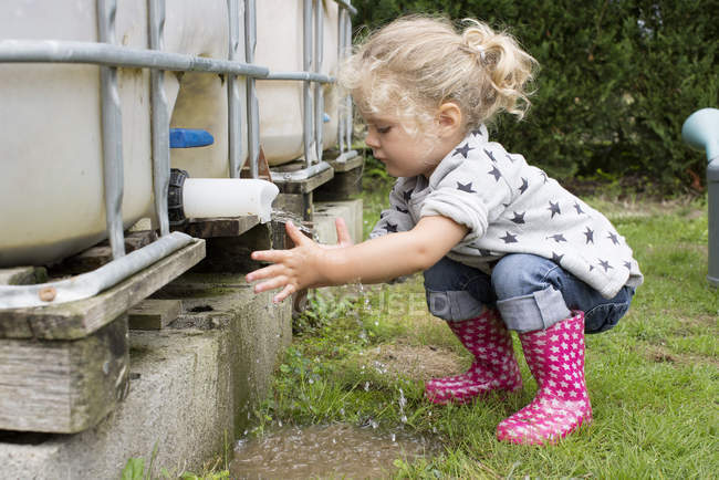 Kleines Mädchen wäscht sich unter Zisterne im Freien die Hände — Stockfoto
