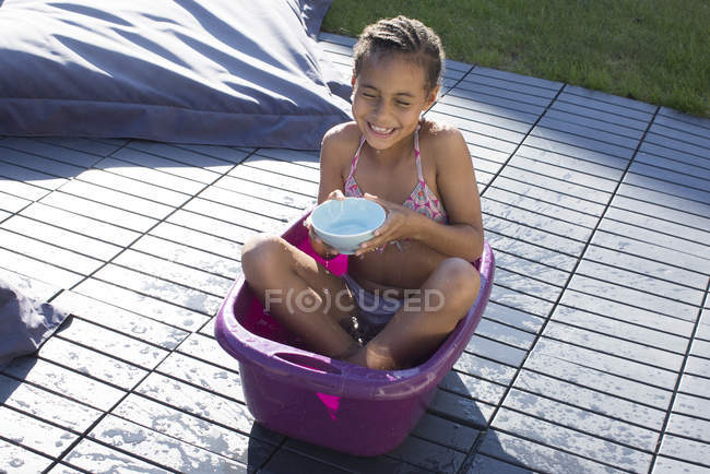 Ragazza seduta nel secchio e giocare con l'acqua — Foto stock