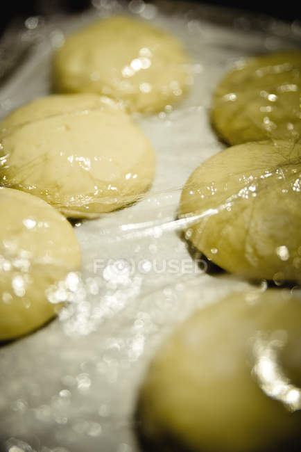 Close up of Dough rising up under cellophane on the table — Stock Photo
