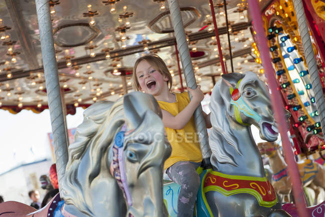 Happy little girl riding on carousel — Stock Photo