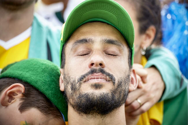 Abanico de fútbol con la cabeza hacia atrás y los ojos cerrados en decepción - foto de stock