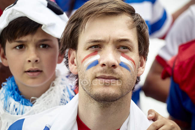 Padre e hijo mirando ansiosamente en el partido de fútbol francés - foto de stock