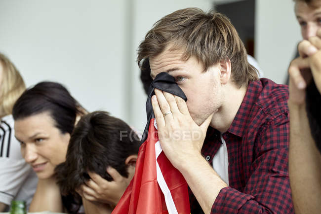Futbolistas alemanes cubriendo caras mientras miran el partido - foto de stock