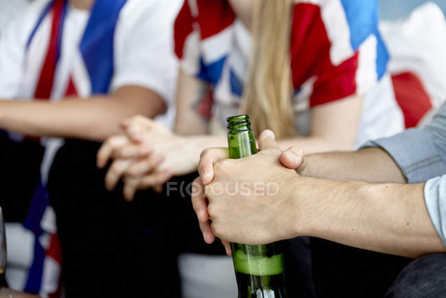 Gros plan d'un passionné de sport tenant une bouteille de bière entre les mains — Photo de stock