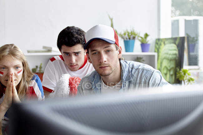 Sports enthusiasts watching match on TV at home — Stock Photo