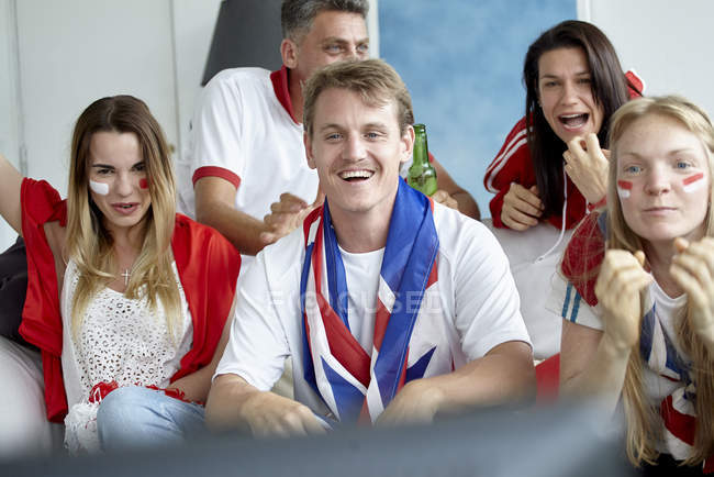 Aficionados al fútbol británico viendo el partido en la televisión en casa - foto de stock