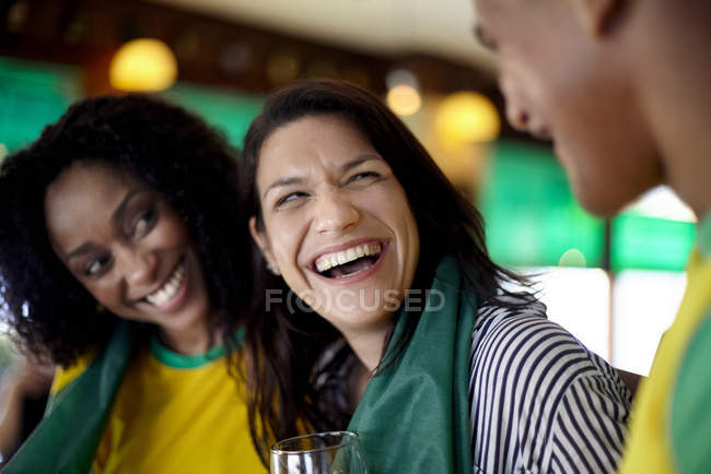Женщины смеются в баре с другом-мужчиной — стоковое фото