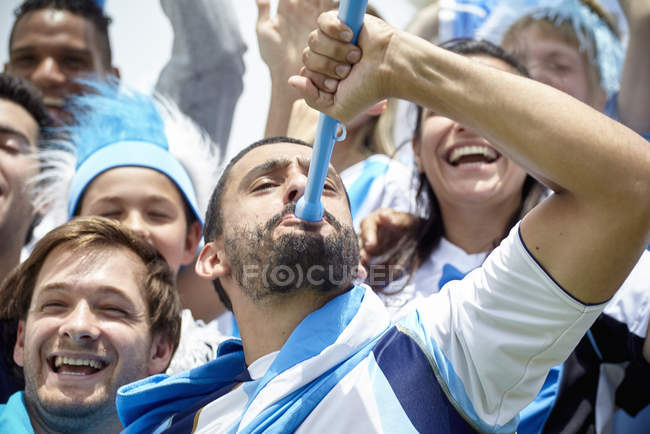 Aficionado al fútbol argentino jugando vuvuzela en el partido - foto de stock
