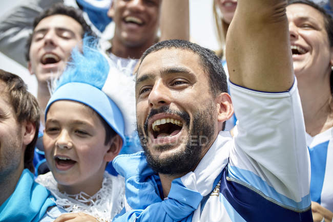 Football fans in colorful clothing cheering at match — Stock Photo