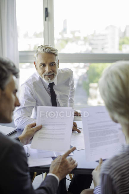 Couple reading document during meeting with mature businessman — Stock Photo