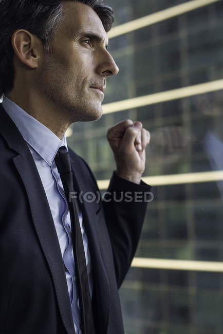 Homme regardant par la fenêtre dans un immeuble de grande hauteur — Photo de stock