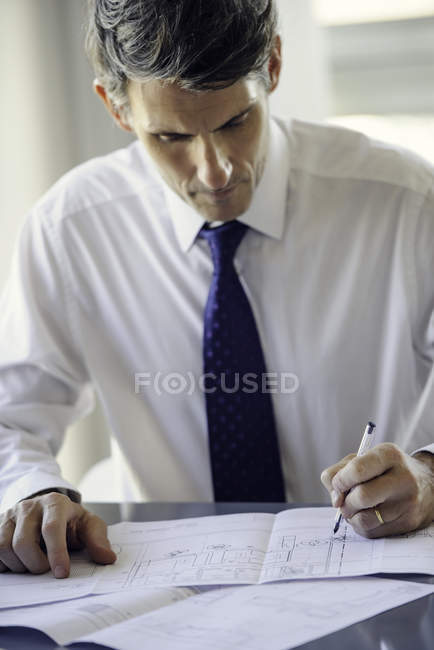 Hombre trabajando con planos en la oficina - foto de stock