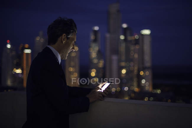 Homme d'affaires sur le toit de grande hauteur en utilisant le téléphone mobile — Photo de stock