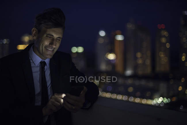Бизнесмен на крыше высотного здания с помощью мобильного телефона — стоковое фото
