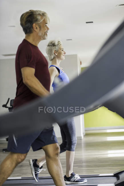 Homme et femme faisant de l'exercice sur tapis roulants — Photo de stock