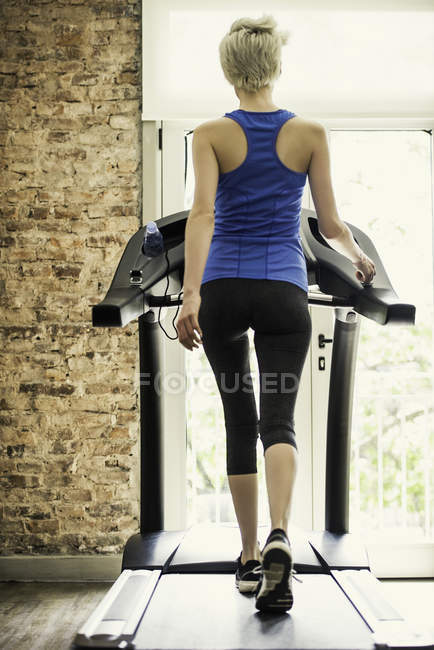 Вид ззаду жінка тренується на біговій доріжці — стокове фото