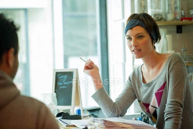 Camarera ayudando a los clientes en la cafetería - foto de stock