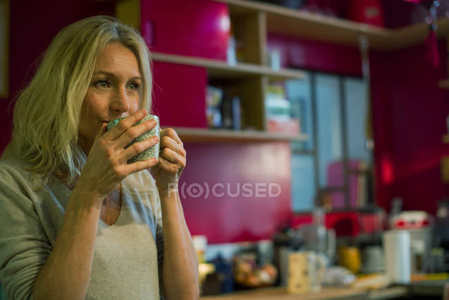 Зріла жінка п'є каву вдома — стокове фото