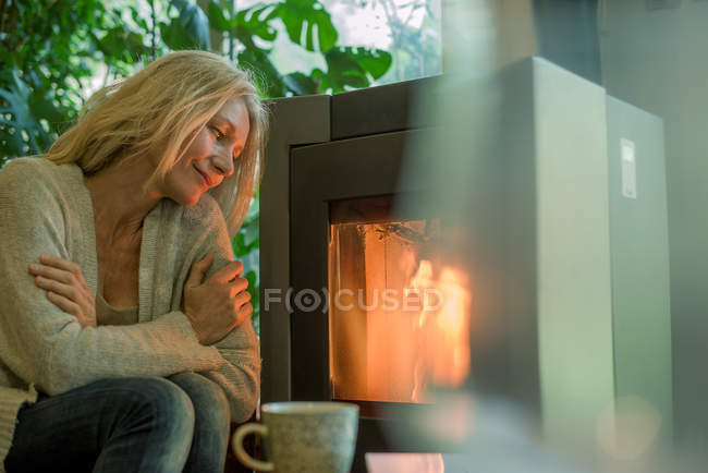 Ältere Frau entspannt sich am Kamin — Stockfoto