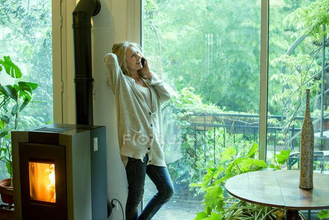 Mujer madura hablando por teléfono celular en casa - foto de stock