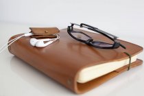 Portátil de cuero con gafas y auriculares - foto de stock