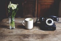 Tasse, Telefon und Maiglöckchen-Strauß — Stockfoto