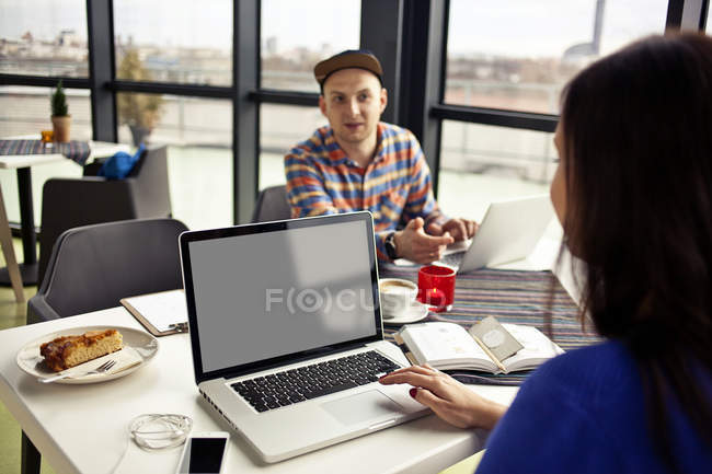 Man and woman at table with laptops — Stock Photo