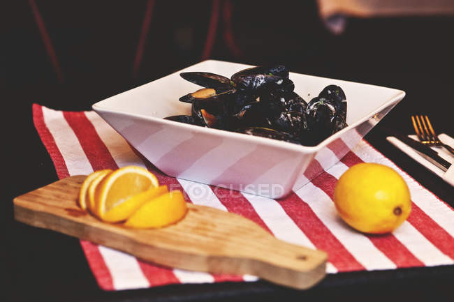 Mussels in white bowl served with lemon — Stock Photo