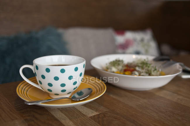 Taza punteada de té y tazón con ensalada - foto de stock