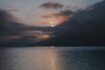 Vue lointaine du coucher du soleil sur les montagnes dans les nuages et la mer — Photo de stock