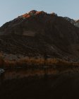 Далекий вид на темную гору и озеро на закате — стоковое фото
