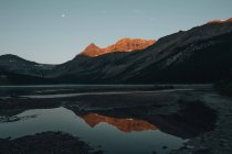 Distant view of mountains lightened by sunset reflecting in Bow lake, Alberta, Canada — Stock Photo