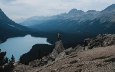Vista diurna de una persona parada en una roca cerca del lago Peyto, Banff, Canadá - foto de stock
