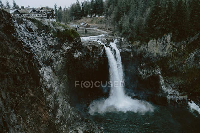 Daytime view of buildings near waterfall in mountains — Stock Photo