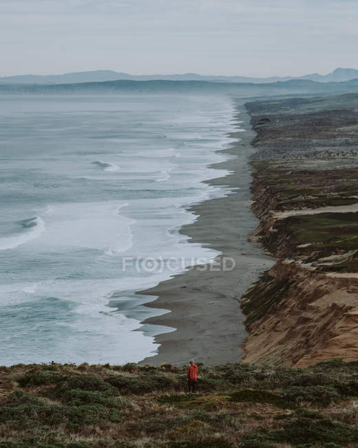 Дневной вид сзади на женщину, стоящую на лугу рядом с национальным побережьем Пойнт-Рейес, округ Марин, Калифорния — стоковое фото
