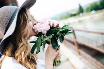 Girl in hat smelling flowers — Stock Photo