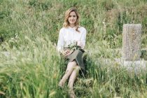 Девушка, сидящая в высокой траве — стоковое фото