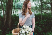 Girl with straw basket and flowers — Stock Photo