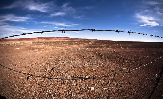 Deserto através de cerca de arame farpado — Fotografia de Stock