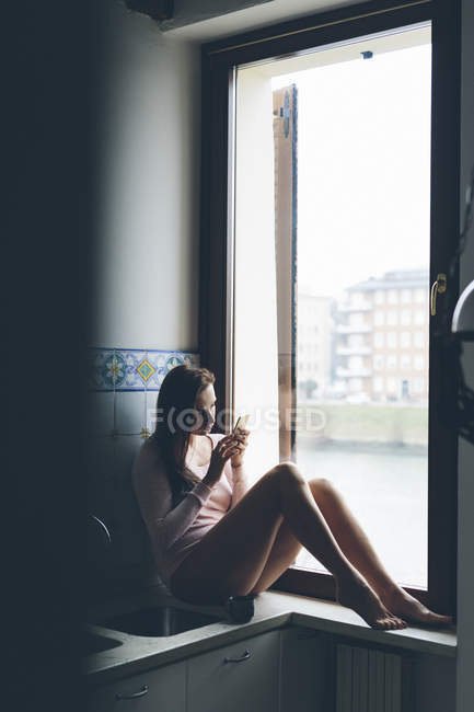 Девушка, сидящая у окна — стоковое фото
