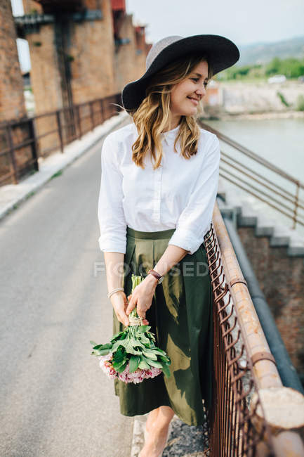 Дівчина в капелюсі з квітами в руках — стокове фото