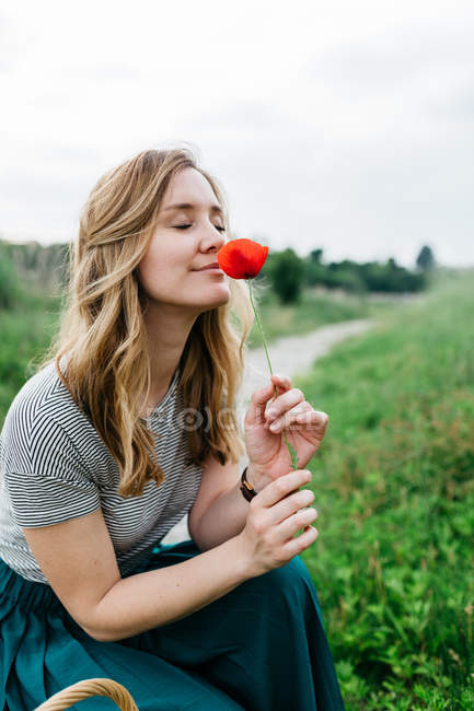 Girl smelling red flower — Stock Photo