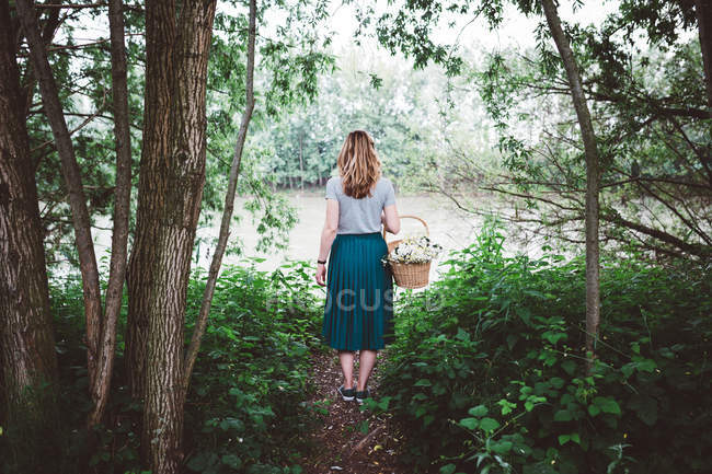Chica en el bosque contra estanque - foto de stock