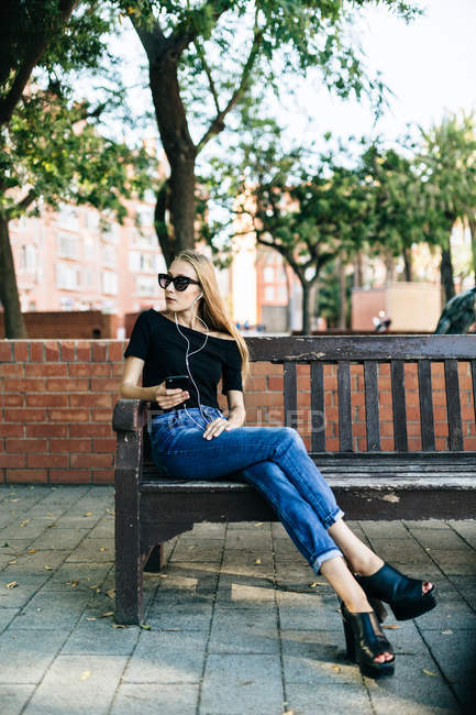 Дівчина в сонцезахисних окулярах тримає смартфон — стокове фото