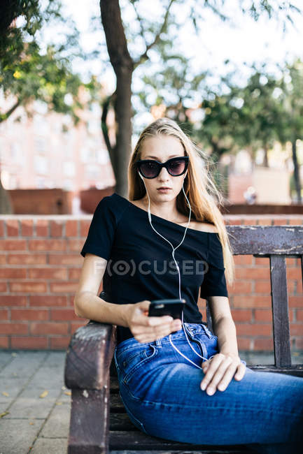 Fille en lunettes de soleil tenant smartphone — Photo de stock