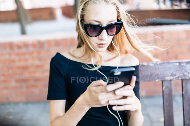 Menina em óculos de sol segurando smartphone — Fotografia de Stock
