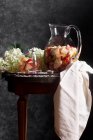 Boisson aux pommes dans une cruche en verre et fleurs — Photo de stock