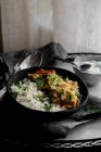 Frango Achari com arroz em tigela preta — Fotografia de Stock